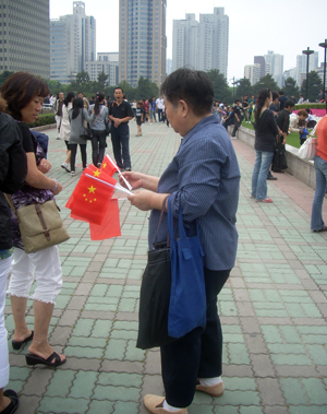 Man on the street in China selling Chinese flags - www.HowCanIRetire.net